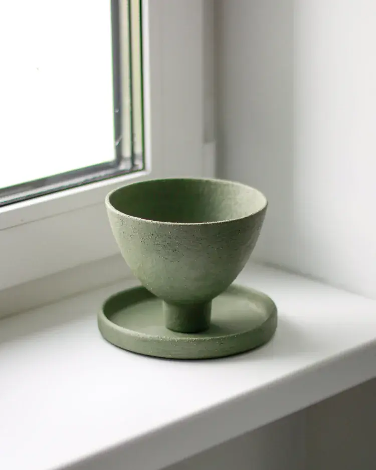 Green ceramic bowl displayed in gallery window
